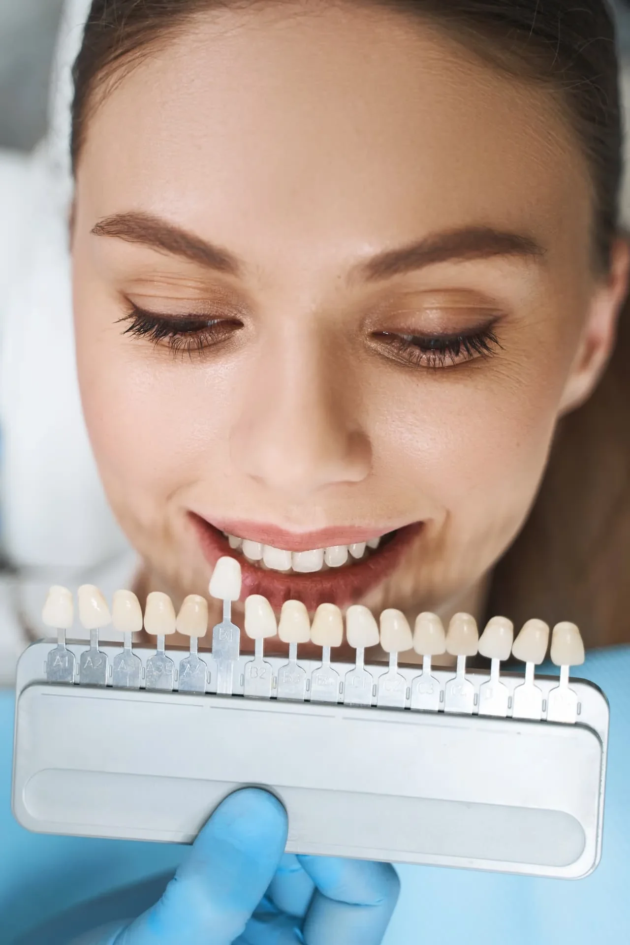 Dental shade guide held beside a patient's smile during a porcelain veneer consultation